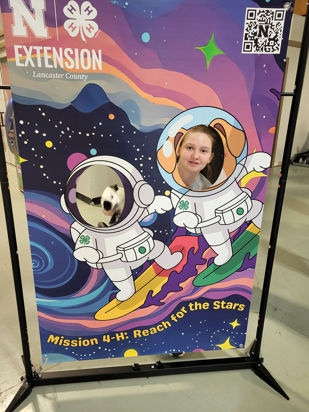 A 4-H youth and her rabbit behind a face cutout banner at the 2026 4-H Spring Rabbit Show.