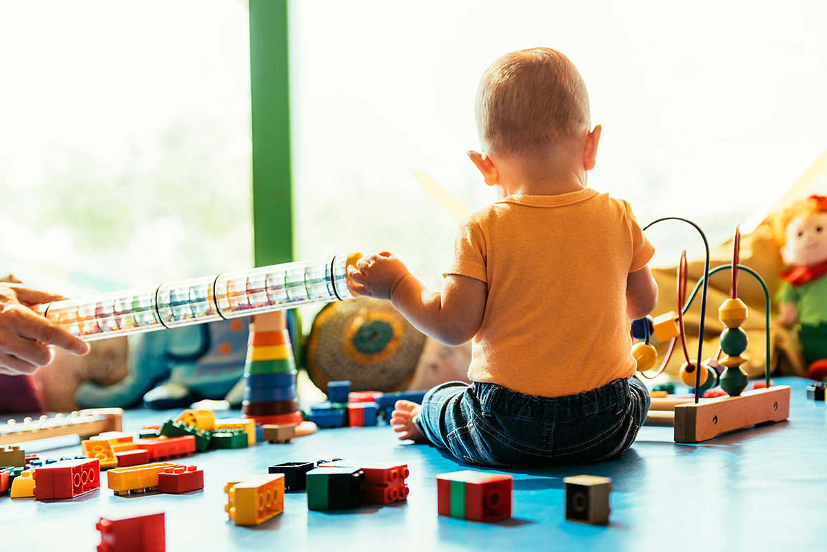 Infant playing with legos and other toys. (Photo stock.adobe.com)