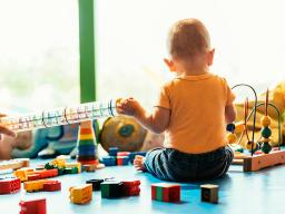 Photo of infant playing with legos and other toys. Photo provided by Adobe Stock.