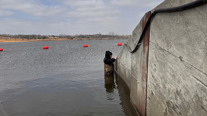 Jake Pittman installs a surface water data logger at Lake Wanahoo north of Wahoo, Neb., on March 5, 2026. The data logger provides continuous water level measurements for the lake.