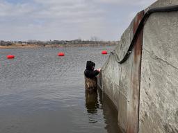 Jake Pittman installs a surface water data logger at Lake Wanahoo north of Wahoo, Neb., on March 5, 2026. The data logger provides continuous water level measurements for the lake.