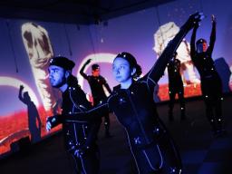 UCARE students in lighted costumes engage in a creative arts performance. (Photo credit: Craig Chandler, University Communications