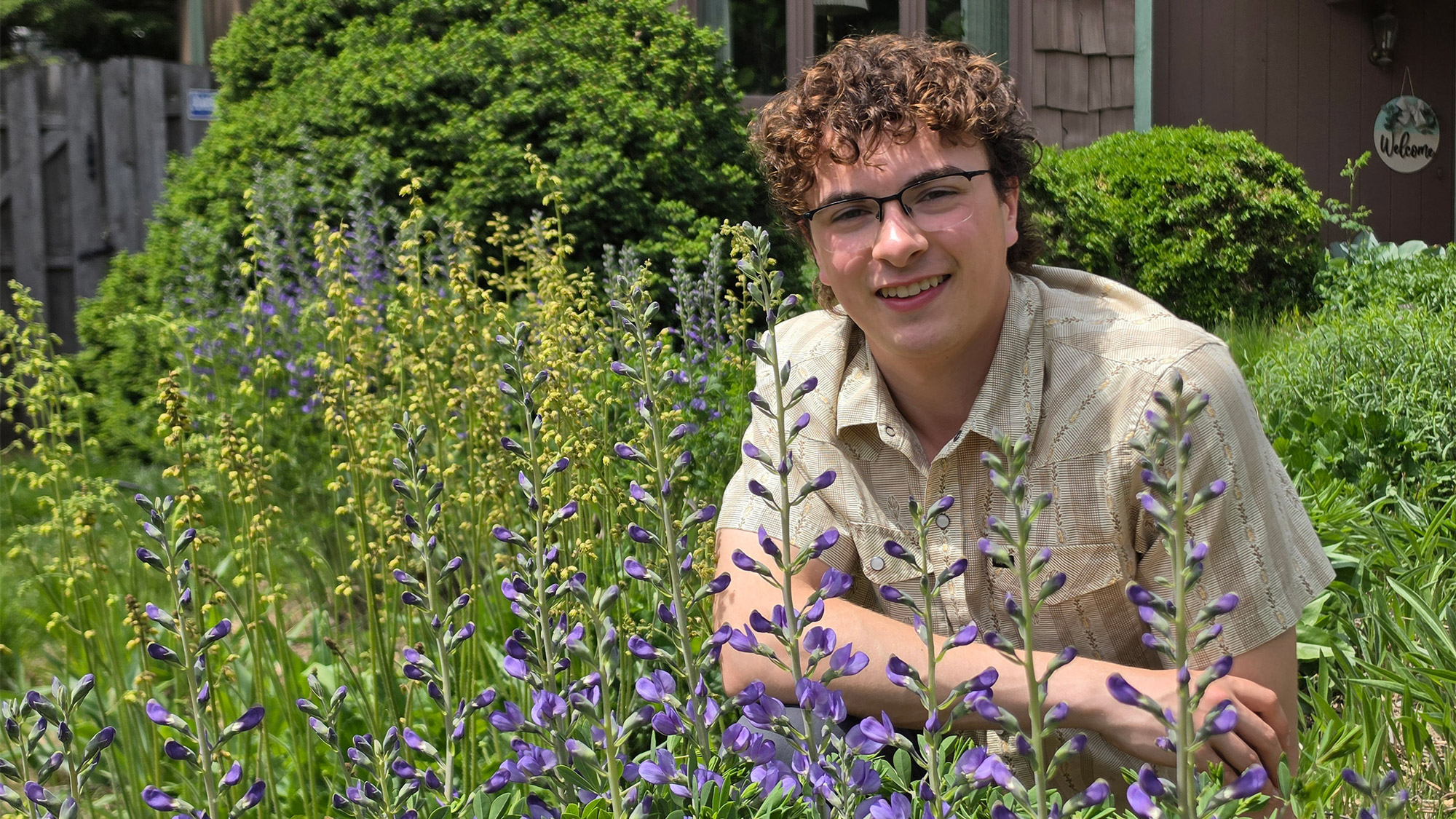 Cole Vredeveld kneels in his native meadow garden at his home, where he experiments with naturalized landscape design. 