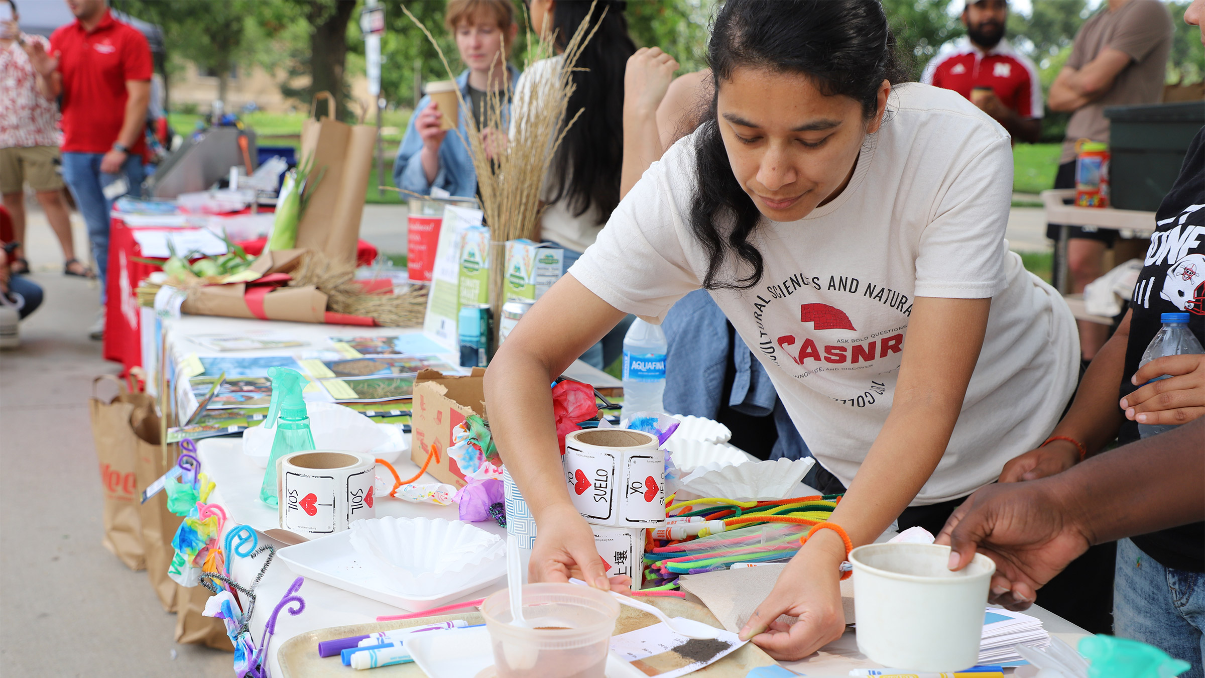 Urmila Manandhar, a doctoral student in the Department of Agronomy and Horticulture, creates a soil profile diagram with a plastic spoon, colored sands and water at the AHGSA booth at the Aug. 9, 2025, Discovery Days.