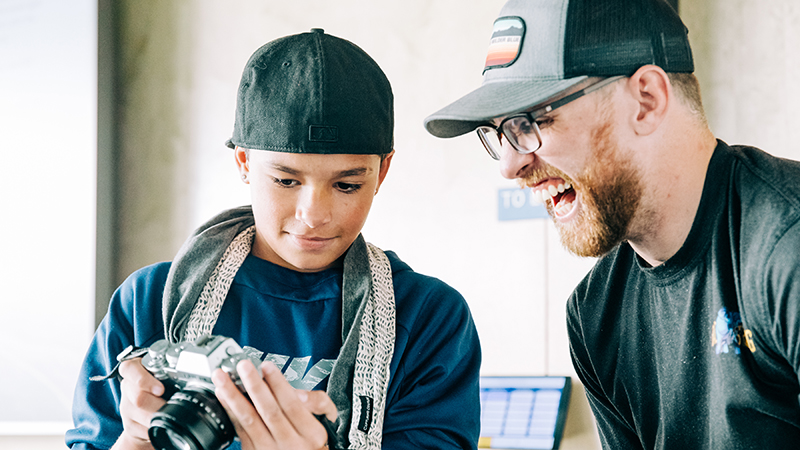 A boy shows Zach Schafer (right) his favorite photos at a Grief through the Lens event at the Kiewit Luminarium in Omaha in August 2018. 