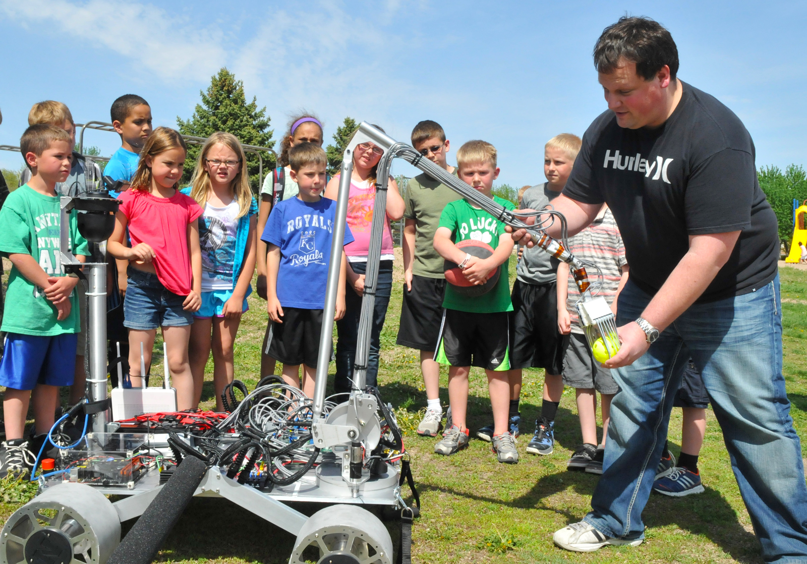 Joe Bartels (right) shows Zeman Elementary students how a robot developed by UNL engineering students will be used to pick up rocks. The robot was developed for a NASA-led robotics competition.