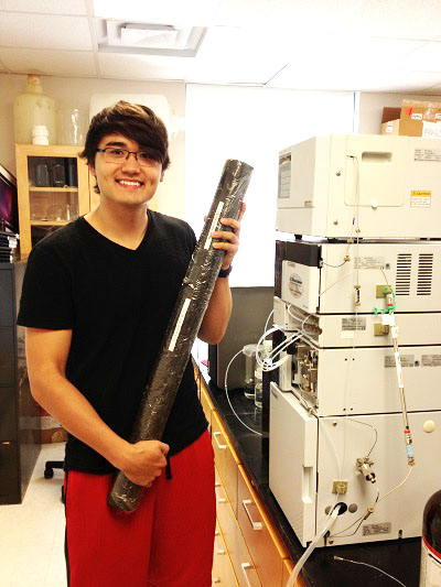 James Reece holding a slow-release permanganate candle next to a high-performance liquid chromatograph (HPLC). (Courtesy photo) 