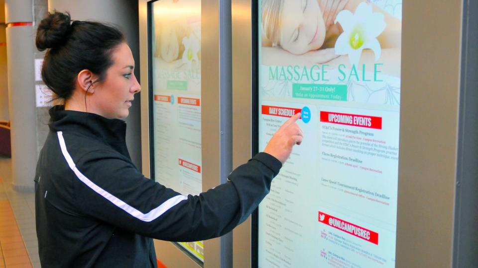 Kaylie Martens, a senior nutrition, exercise and health sciences major, uses the new digital touchscreen in the Campus Rec Center on City Campus. The boards are part of a campuswide initiative. (University Communications)