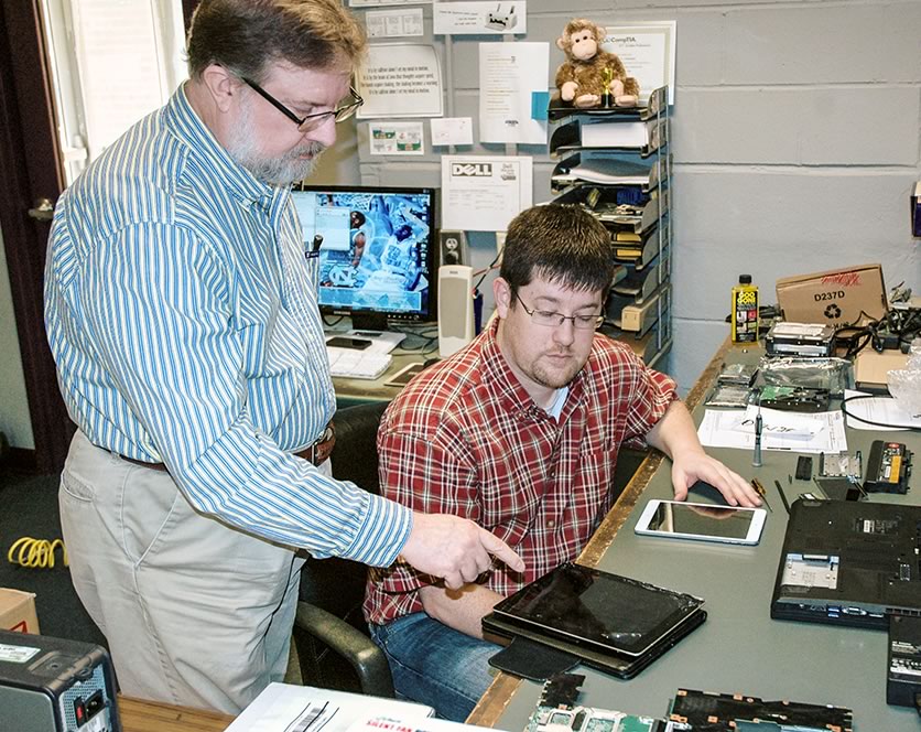 Michael McNeil and Nathan Clements look over an iPad for repair.