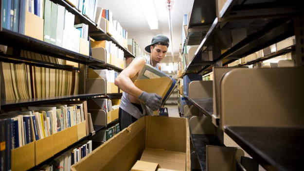 Jonny Reico with VonRentzell Movers packs books in the third floor stacks of Love Library South as part of the Learning Commons Project. Work on the project started in July.
