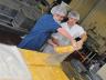 Jonathan Hnosko (left) and Andrew Donovan, a student employee, load a 25-pound block of Husker-N-Gold cheese into a bag that will be vacuum-sealed. (Troy Fedderson | University Communications)