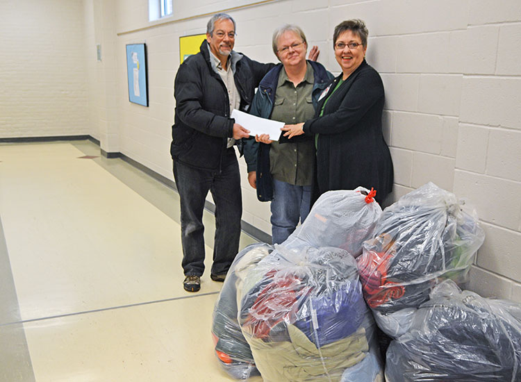 Dennis Ferraro (from left) and Dee Ebbeka, members of the School of Natural Resources' community engagement committee, present Clare Nelson with donations on Dec. 9. (Mekita Rivas | Natural Resources)