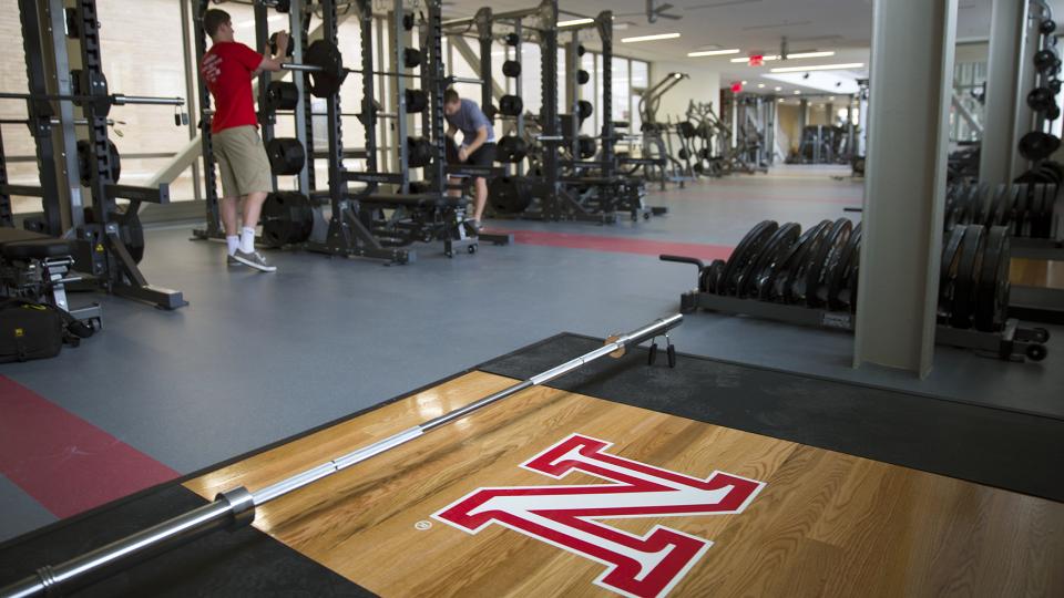 UNL students and Campus Recreation employees (from left) Joe Grobeck and Nate Morhardt place weights on a compound rack in the new East Campus Recreation and Wellness Center. (Troy Fedderson | University Communications)