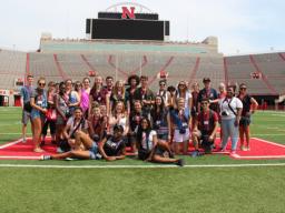 Media Academy students pose at Memorial Stadium with team leaders and professors