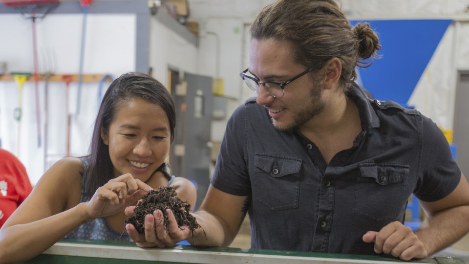 UNL students Vivian Nguyen (left) and Cale Brodersen examine worms that are turning food waste into compost at Big Red Worms, a new composting operation in west Lincoln. | Troy Fedderson, University Communications