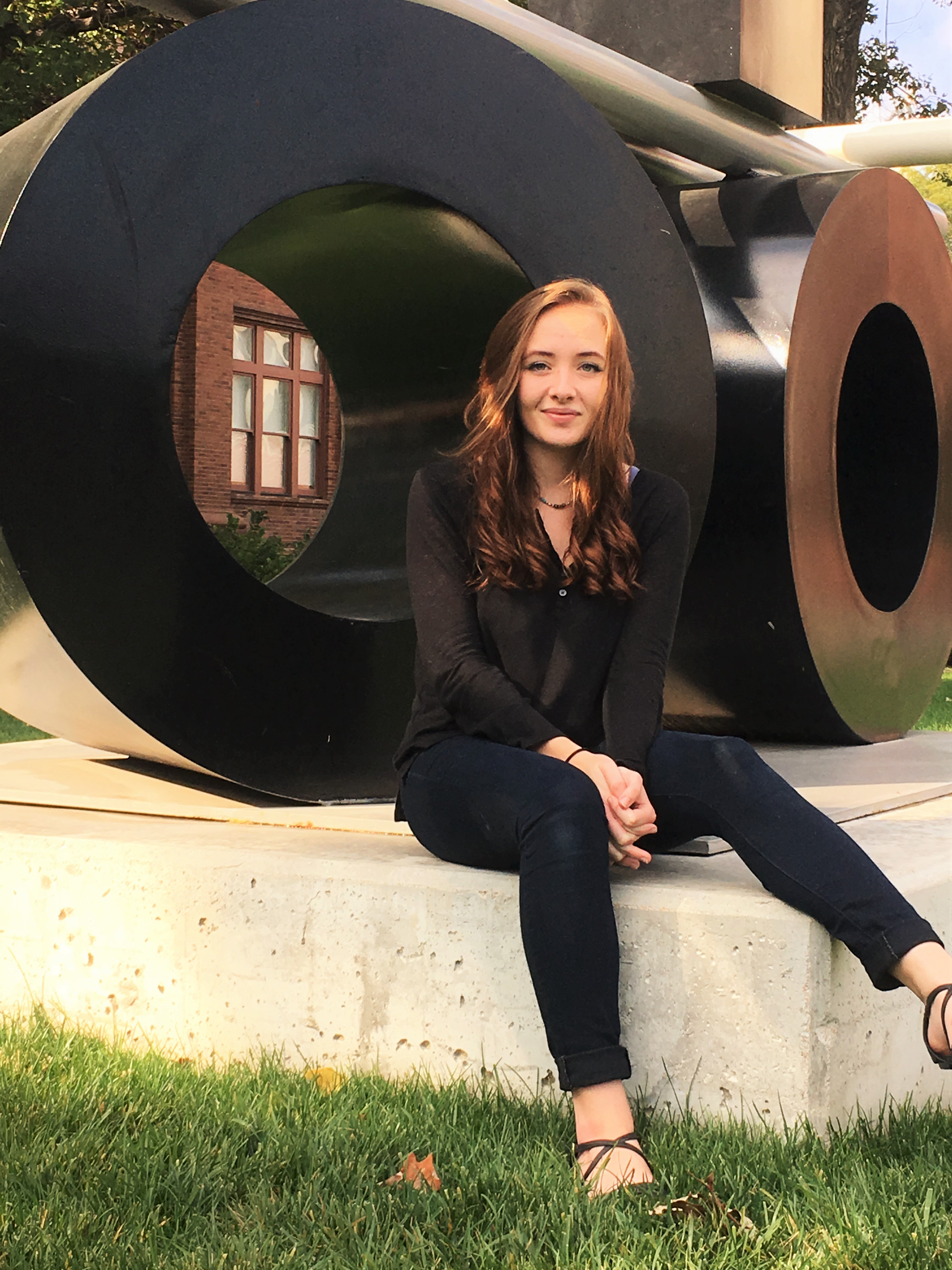 Anika Zempleni sits in front of Fletcher Benton’s sculpture, “Balanced/Unbalanced Wheels #2” at the University of Nebraska-Lincoln.
