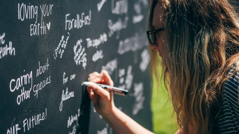 A student writes about what sustainability means to her on a Nebraska-shaped chalkboard during the university's 2016 Earth Day celebration in April.