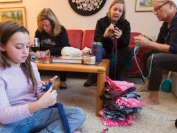 Nylah Mossop (left) uses her fingers to knit a scarf during the launch of the "Scarves for Kids" project on Nov. 20. The event was organized by Jo Ann Emerson (right) and Sandra Williams (not pictured). Other participants included (left of Emerson) Amanda