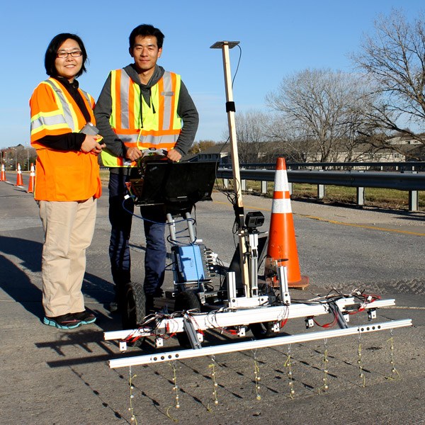 Dr. Jinying Zhu (left) with graduate student Hongbin Sun showing the cart rigged with the metal bead system.