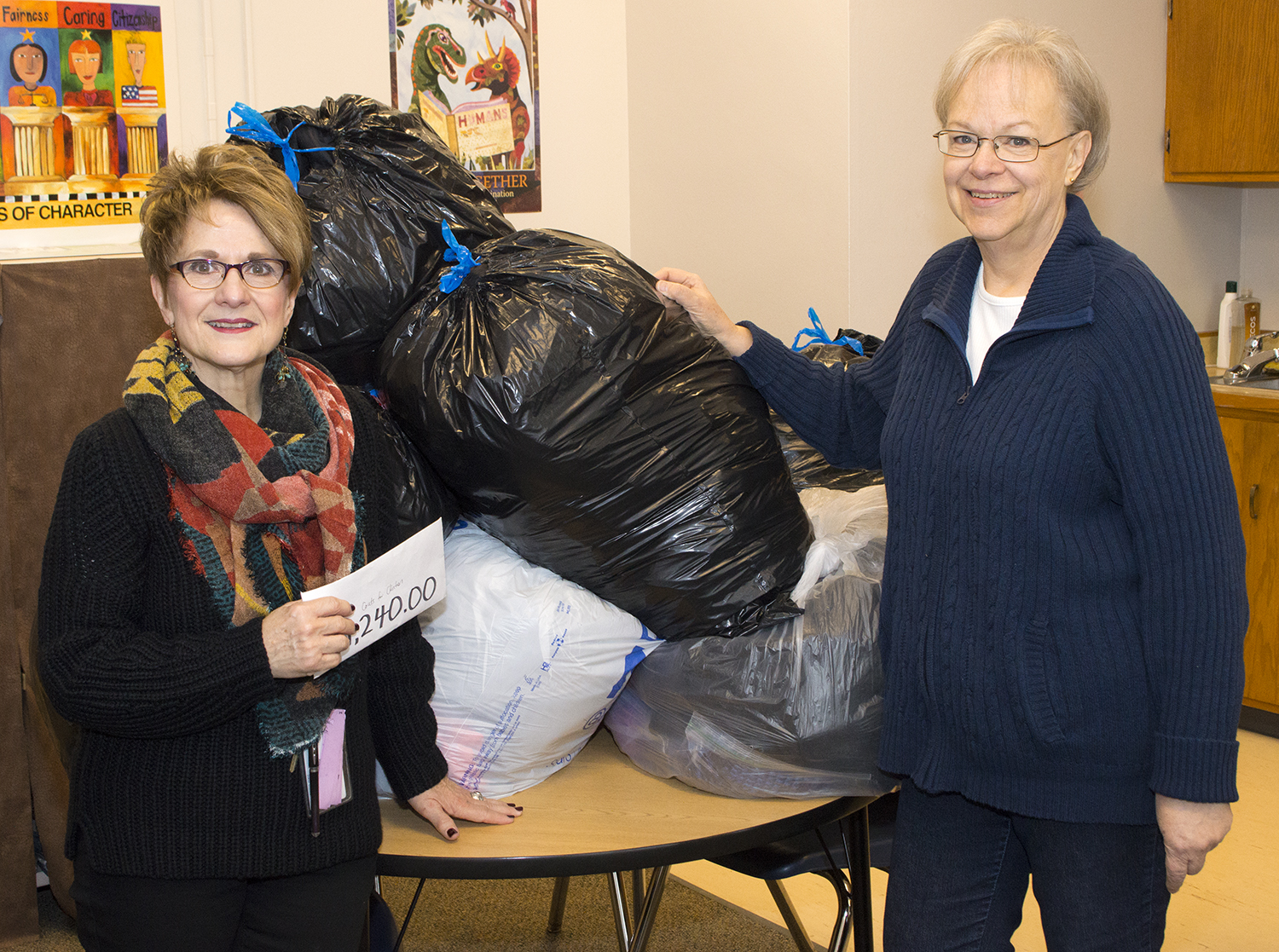 Linda Kern, Clinton Elementary faculty care coordinator, accepts the Coats for Clinton donations from Dee Ebbeka, SNR Community Engagement Committee member, on Dec. 9 at the school. | Shawna Richter-Ryerson, Natural Resources