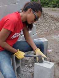 Student chops bricks to build hurricane resistant homes in Guatemala.