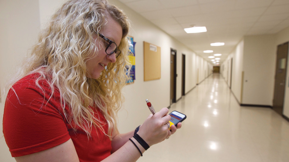 Courtney Schnell, a graduate assistant with Campus Recreation's wellness and nutrition team, writes down distance as she maps a walking path on the first floor of Nebraska Hall on Feb. 22. | Troy Fedderson, University Communications