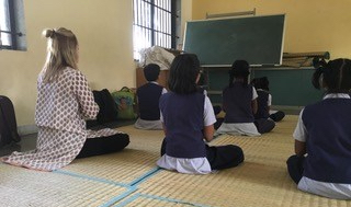 Anubhuti students help teach Jessica Fetrow proper yoga and meditation poses