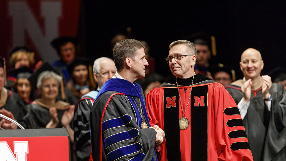 Hank Bounds (left), president of the University of Nebraska system, congratulates Chancellor Ronnie Green after officially installing Green as Nebraska's 20th chancellor. Gov. Pete Ricketts applauds in the background. |  Craig Chandler, University Communi