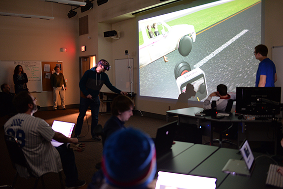 Film and New Media Senior Ben Hartzell (in VR goggles on left) shows the progress of his team's final project in class on April 10. Photo by Michael Reinmiller.