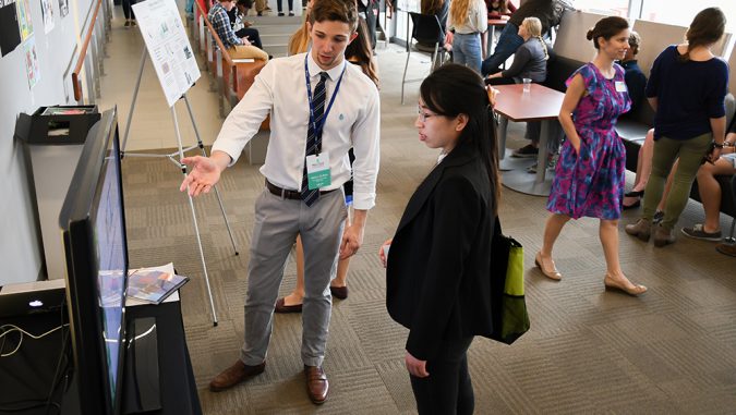 Conference participants interact with University of Nebraska-Lincoln students displaying infographics and other projects as part of the Student Showcase and Art Show at the Nebraska Innovation Campus Conference Center. | Courtesy WFI
