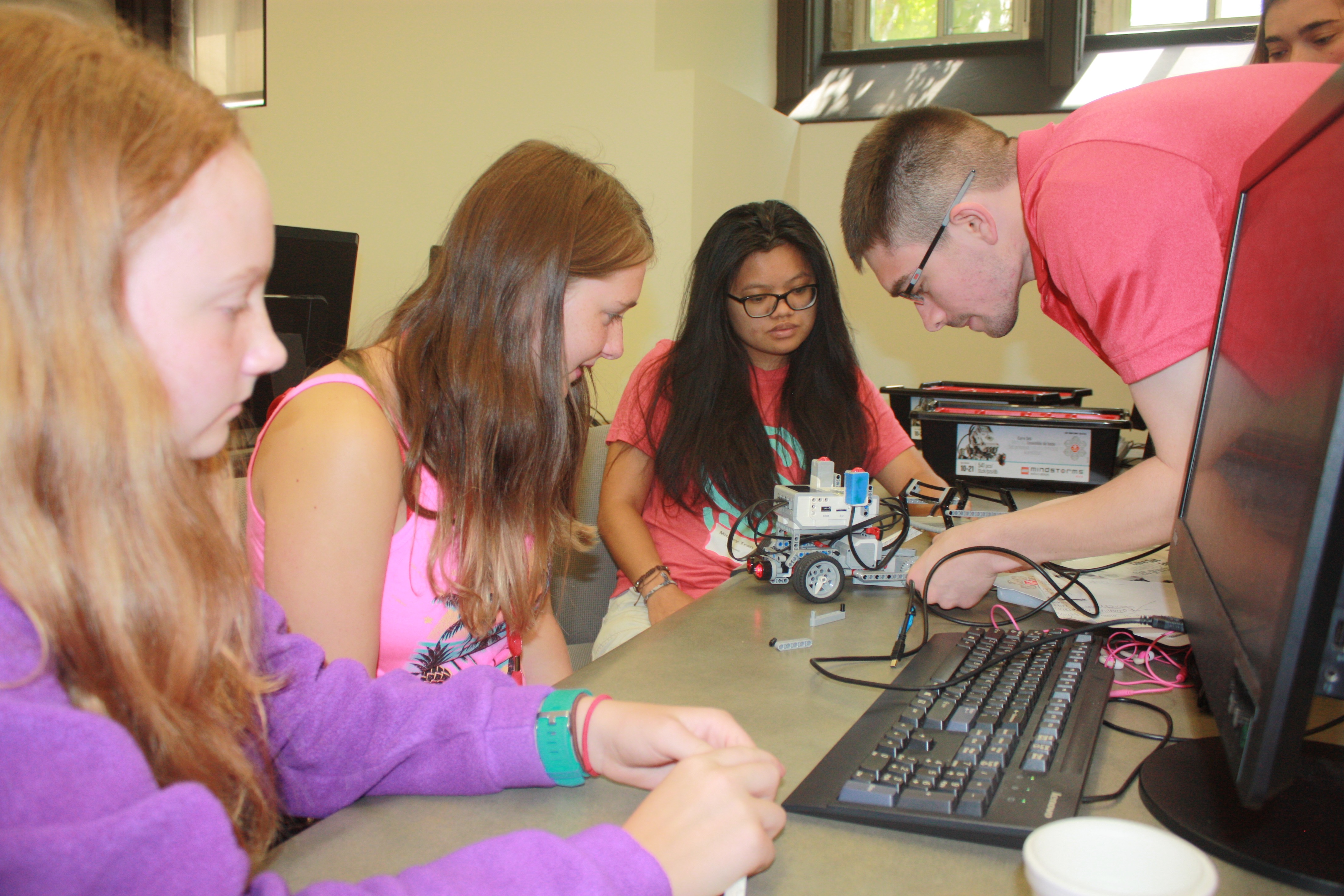 CSE students Mickey Tran and Tyler Barker help two Girl Scouts program a LEGO robot at this year's summer computing camp.
