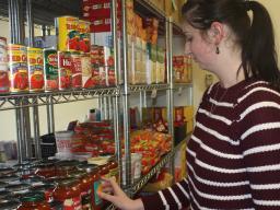 Jessica Lanctot, graduate assistant in the Huskers Helping Huskers Pantry+ adds donated pasta sauce to the pantry shelf.