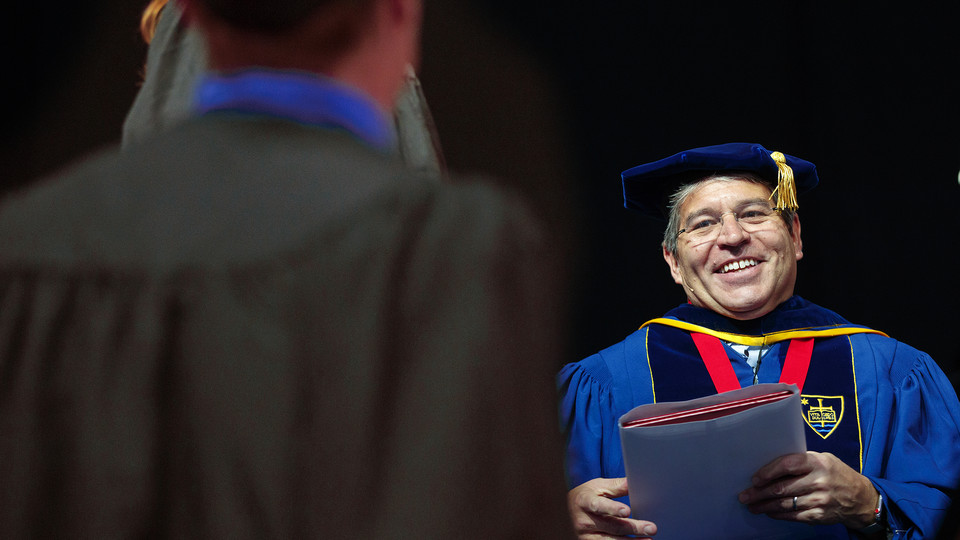 Lance C. Pérez prepares to hand a diploma to an engineering student during the undergraduate commencement ceremony on May 5. Pérez has been named dean of engineering. (University Communication photo)