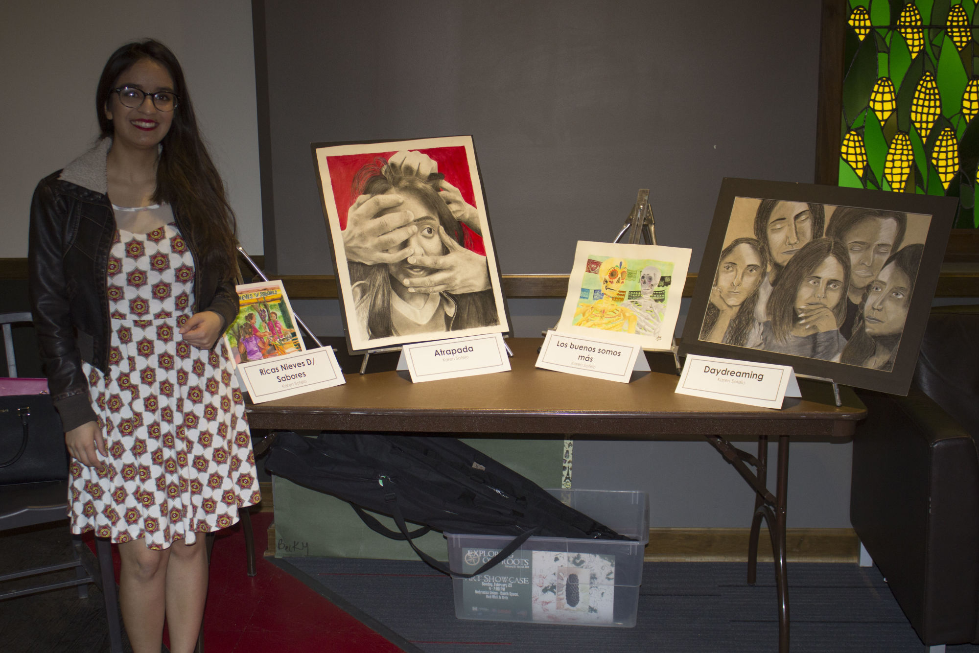 Karen Sotelo stands with her art pieces at the Exploring Our Roots art exhibition.