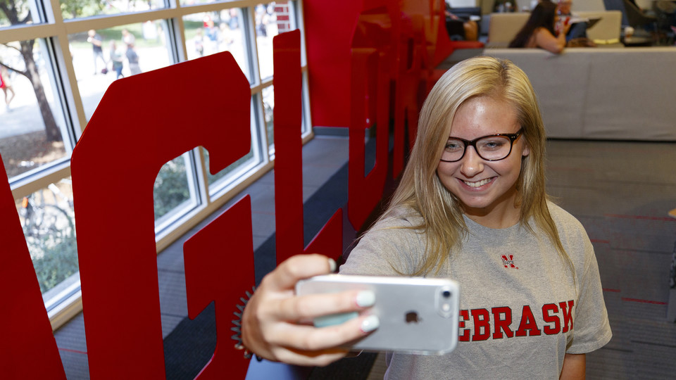 Husker Alyssa Frederick takes a photo next to the "Glory" sign in the Nebraska Union. The "Grit" and "Glory" signs, along with related sidewalk art and a website, appeared the week of Aug. 20. | Craig Chandler, University Communication