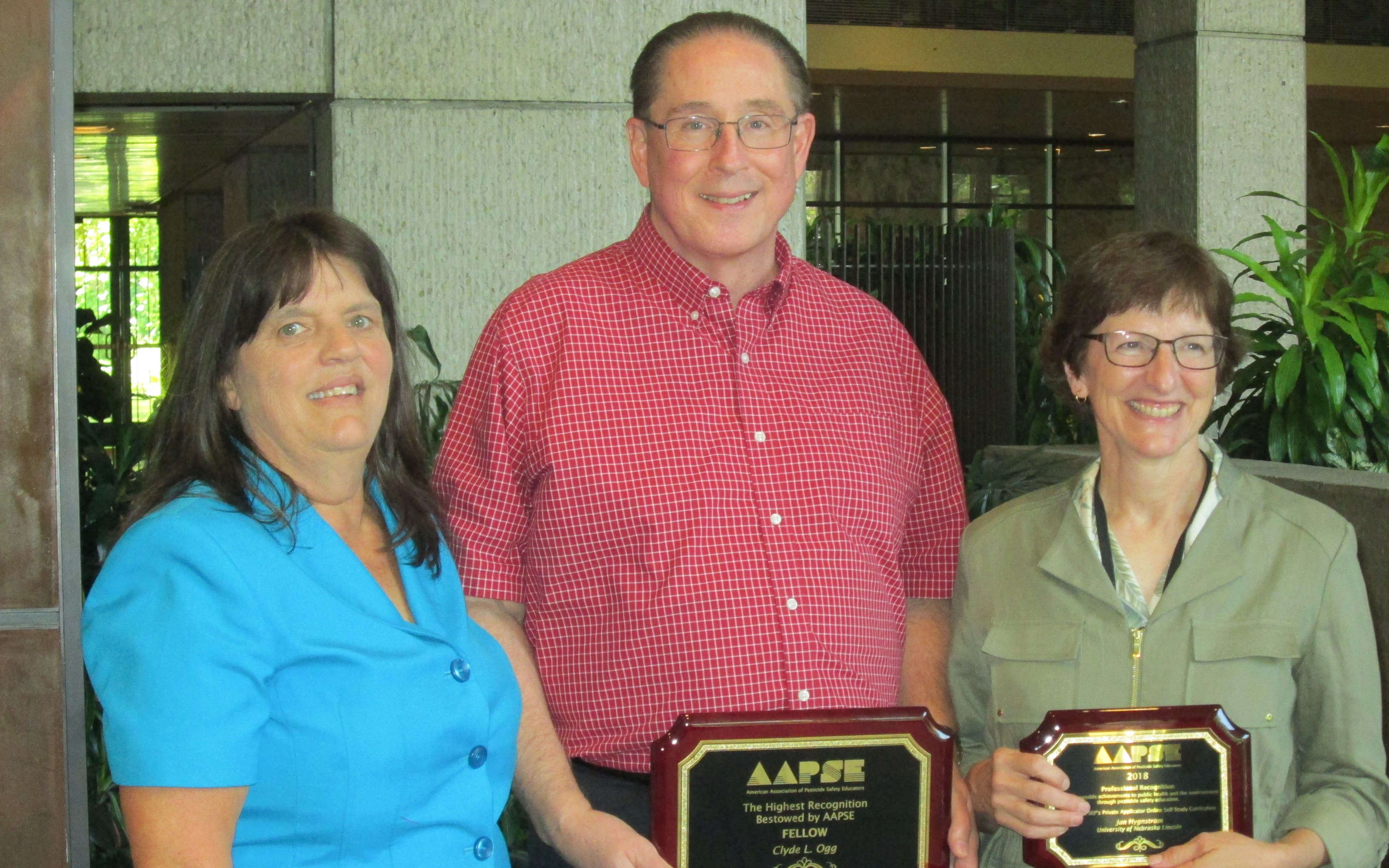 Clyde Ogg, center, and Jan Hygnstrom, right, receive national awards from the American Association of Pesticide Safety Educators. Congratulating them is Kerry Richards, AAPSE president.